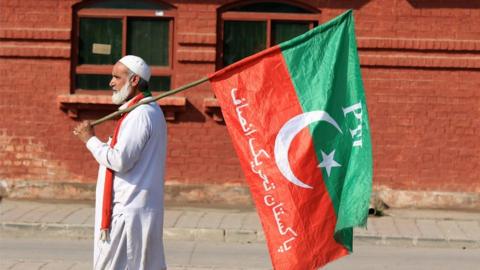 A supporter of the Pakistan Tehrik-e-Insaf (PTI) political party carries his party's flag as supporters gather to protest as they allege rigging in the general elections, in Peshawar, Pakistan, 11 February 2024.