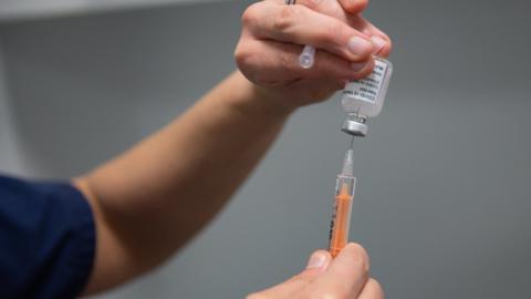 A health worker fills a syringe with vaccine