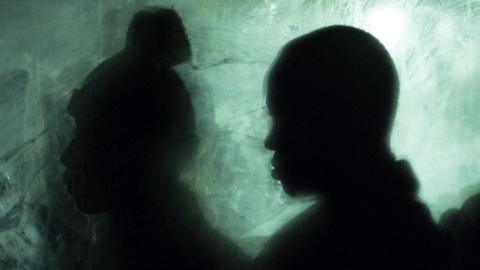 Silhouettes of two people inside a bus waiting to be transferred