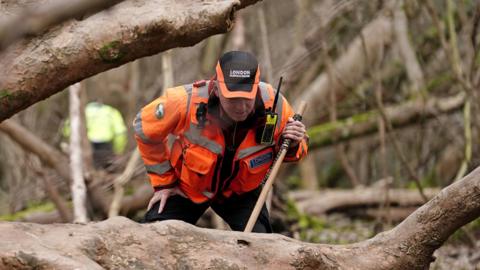 An officer from London Search and Rescue (LONSAR) in woodland near Brighton