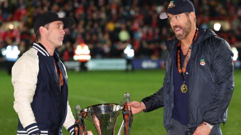 Rob McElhenney (left) and Ryan Reynolds hold the National League trophy