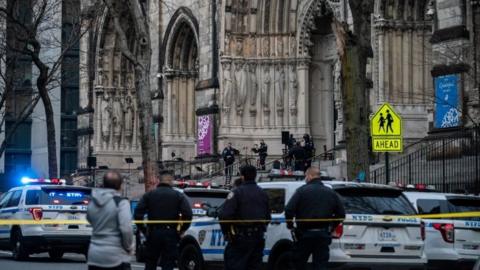 Officers stand outside the Cathedral of St John the Divine in Manhattan after a gunman opened fire