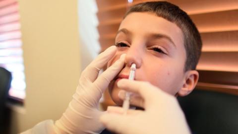 A young boy getting a nasal flu spray vaccine