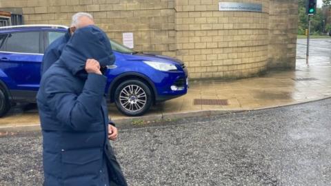 Mr Bhimjiyani, covering his face as he left Northampton Crown Court