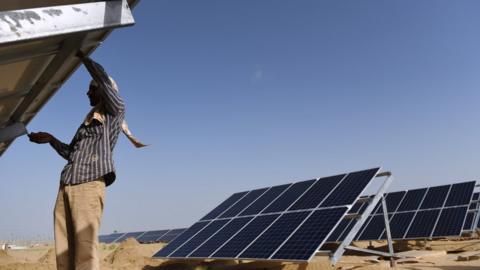 An Indian worker fixes a solar panel at the under construction Roha Dyechem solar plant at Bhadla