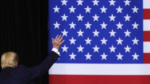 President Donald Trump waves to the audience while departing from the podium