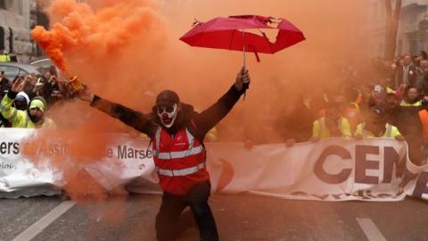 A protester holds a smoke torch during a demonstration against pension reforms in Marseille, France