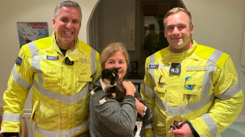 two firefighters and a woman holding a cat