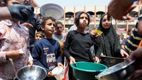 Palestinians gather ta receive chicken meals cooked by Ghetto Central Kitchen