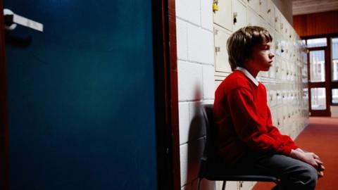 School child sat outside office