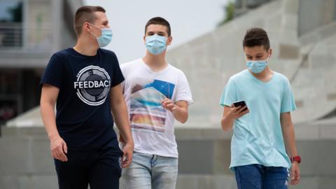 Teenage boys wearing masks walk in the street in Belgrade, Serbia