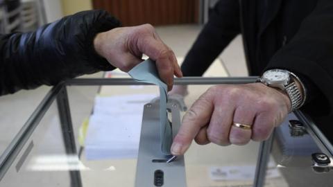 A woman casts her ballot at a polling station