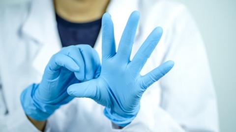 Close up of a person putting on blue medical gloves