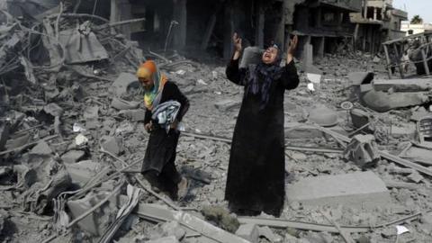 A Palestinian woman pauses amid destroyed buildings in the northern district of Beit Hanun in the Gaza Strip during an humanitarian truce on 26 July 2014