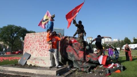 A defaced statue of Queen Victoria lies after being toppled during a rally