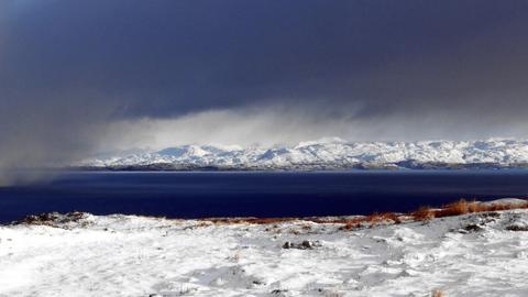 Dark clouds over the sea with snow lying on the surrounding ground in Kilmory, Scotland