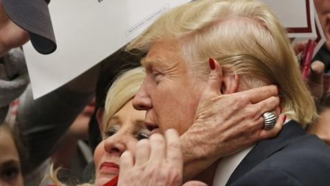 A supporter puts her hand to Donald Trump's face at a rally