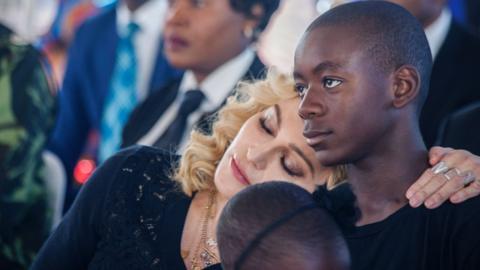 US pop star Madonna (left) rests her head on the shoulder of her adopted son David Banda during the opening ceremony of the Mercy James Children's Hospital at Queen Elizabeth Central Hospital in Blantyre, Malawi, on 11 July 2017.