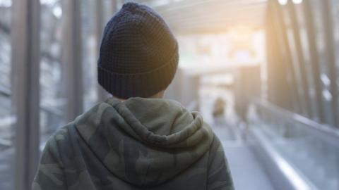 A stock image of teenage boy wearing a hoodie and a hat