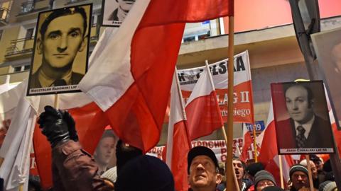 Pro-government activists hold portraits of some of the victims of the 1981 martial law and shout slogans at a passing anti-government demonstration marching through central Warsaw