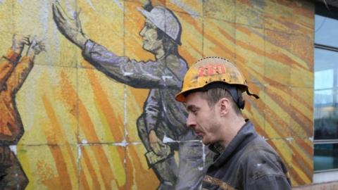 A miner walks past a mural mosaic at the coal mine near Karvina, Czech Republic, after an explosion