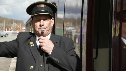 Conductor blows whistle as train leaves Oswestry