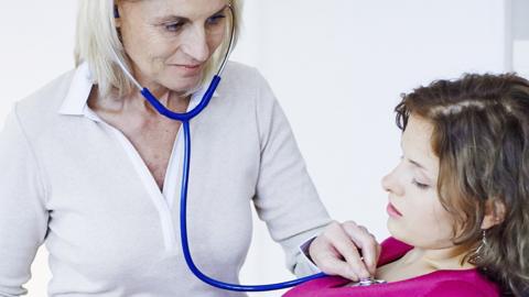 A GP listening to a patient's heart