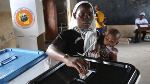 Voter putting ballot paper in a box