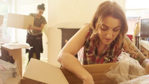 Two women unpack boxes in a new home