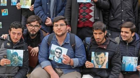 University of Tehran students hold pictures of victims during a memorial after the plane crash