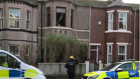 Police cars and officer outside terraced house where fire was