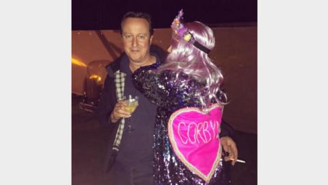 A festival reveller hugs David Cameron