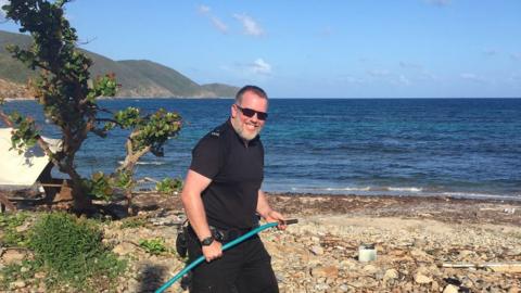 PC Gareth McSherry carrying a hose on a beach