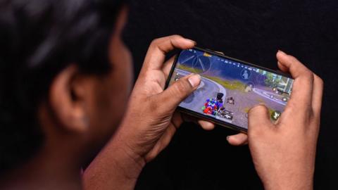 A young man in New Delhi playing a computer game on his mobile phone