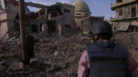 Journalist looking over rubble in Mosul towards mosque (21 June 2017)
