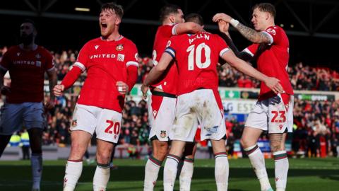 Wrexham players celebrate after Paul Mullin scored his second goal against Mansfield