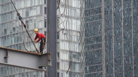 A worker stands on a beam on a construction site in Beijing