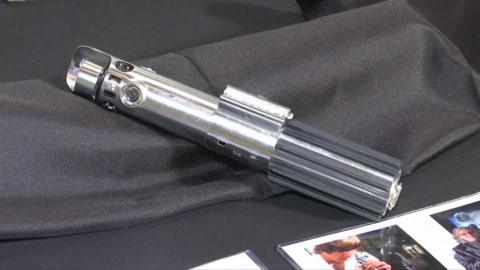 A lightsaber listed as Luke Skywalker's weapon from the 1977 film Star Wars lying on display