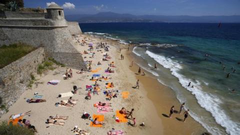 tourists enjoy a day out at the Citadel Beach in central Ajaccio on the French Mediterranean island of Corsica