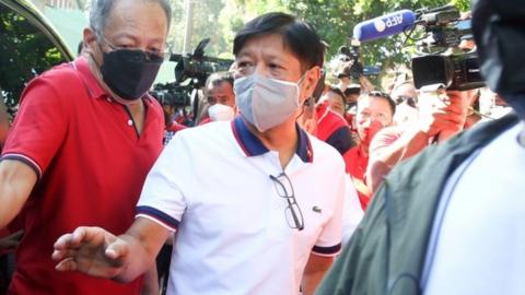 Presidential candidate Ferdinand "Bongbong" Marcos Junior (C), son of former president Ferdinand Marcos, boards a vehicle after casting his ballot at an elementary school