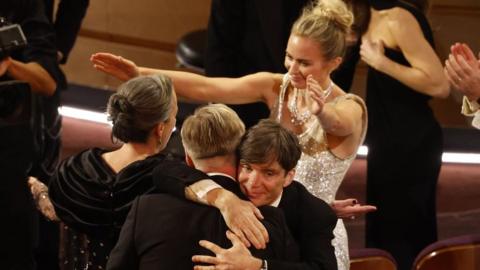 Cillian Murphy (2-R) embraces Christopher Nolan (2-L) as Emily Blunt (R) reaches for Emma Thomas (L) after the film Oppenheimer won the Oscar for Best Picture