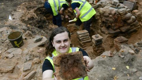 A man holds up a piece of archaeology