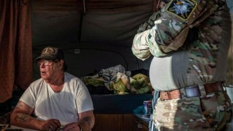 In this file photo taken on March 20, 2019 Striker (L), the leader of the Constitutional Patriots New Mexico Border Ops Team militia, speaks with Viper (R), who go by aliases to protect their identity, inside the team"s camper while discussing logistics on a group chat near the US-Mexico border in Anapra, New Mexico. - The FBI has arrested a member of an armed rightwing militia group accused of illegally detaining migrants at the US-Mexico border, officials said on April 20, 2019. New Mexico Attorney General Hector Balderas described Larry Mitchell Hopkins, who also goes by the name of "Striker," as a "dangerous felon who should not have weapons around children and families."