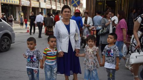 This file photo taken on June 4, 2019 shows a Uighur woman waiting with children on a street in Kashgar in China's northwest Xinjiang region.