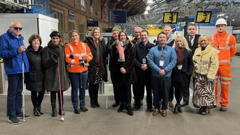 15 people gathered on a train platform