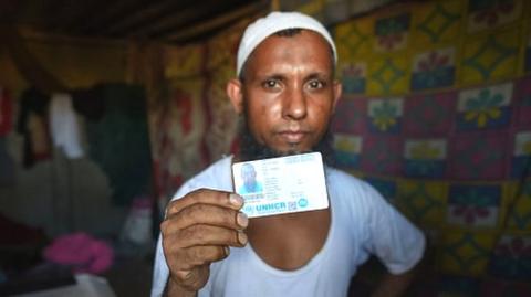 A refugee living at the Rohingya refugee camp holds up his UNHCR card at Kalindi Kunj on August 17, 2022 in New Delhi.