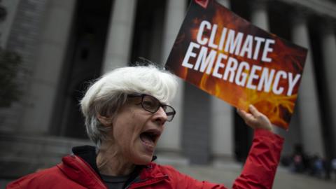 A protester shouts slogans and holds a climate emergency placard protesting against Exxon Mobil before the start of a trial the company faced in 2019.