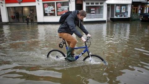 A cyclist rides through floodwater in Datchet