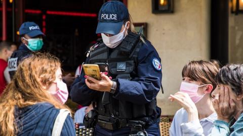 French police officers control customers' health passes at a bar in Paris