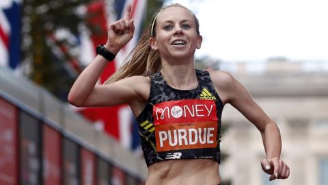 Charlotte Purdue holds up her fist while running the London marathon